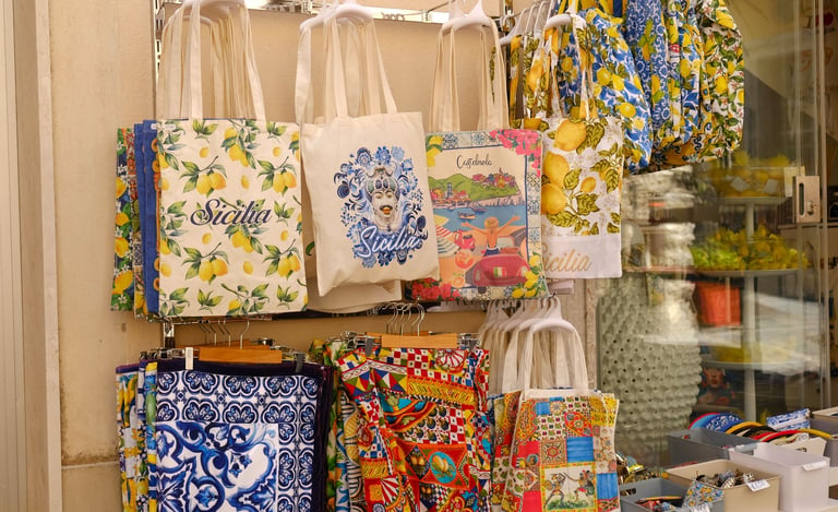 Display of colorful printed tote bags and accessories in a souvenir shop