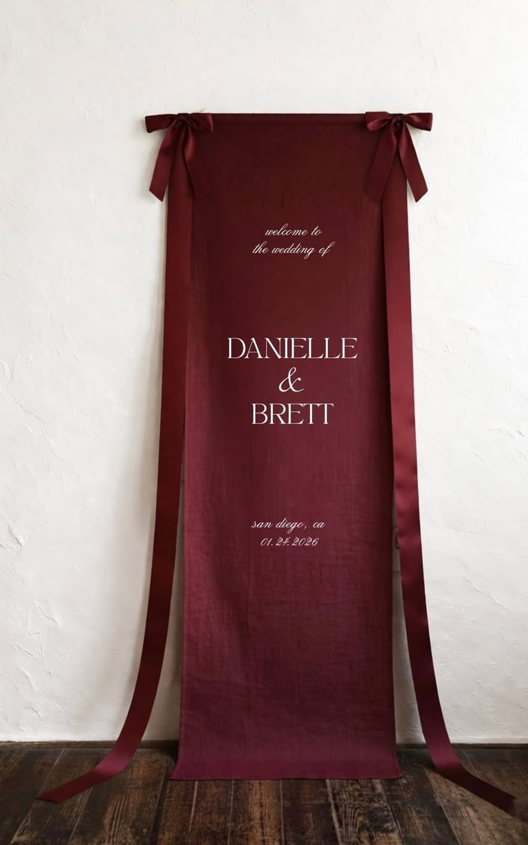 Burgundy wedding banner with ribbon ties displaying welcome message, couple names Danielle and Brett, and San Diego date 01.23.2026