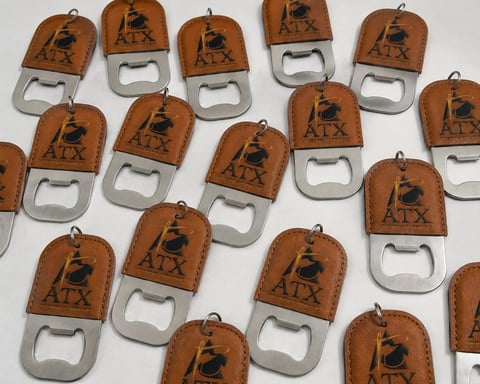 Collection of leather bottle openers with horse and rider etching and metal opener bases arranged on white background