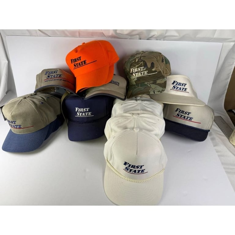 Collection of First State branded baseball caps in various colors including orange, navy, tan, and white arranged on a white surface