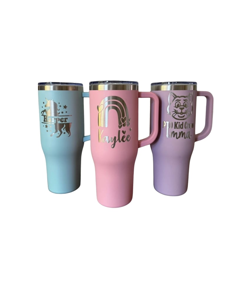 Three personalized tumbler cups in blue, pink, and purple