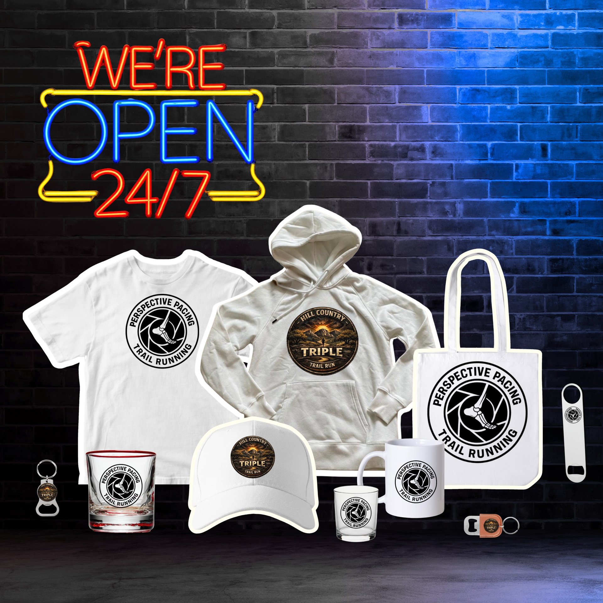 Neon Were Open 24/7 sign above merchandise display including branded t-shirt, hoodie, cap, tote bag, and coffee accessories on brick wall background