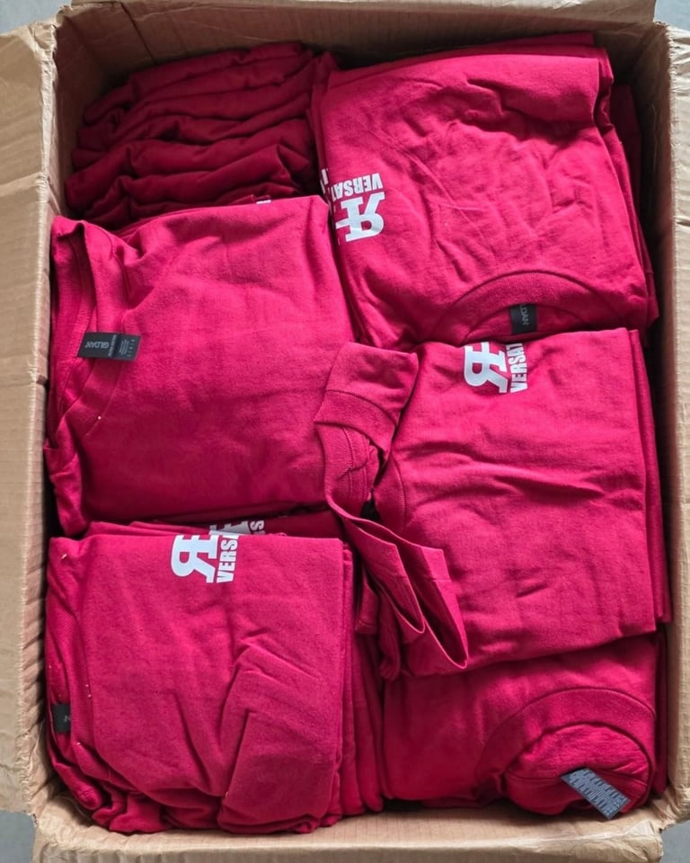 Cardboard box filled with folded pink and red garments