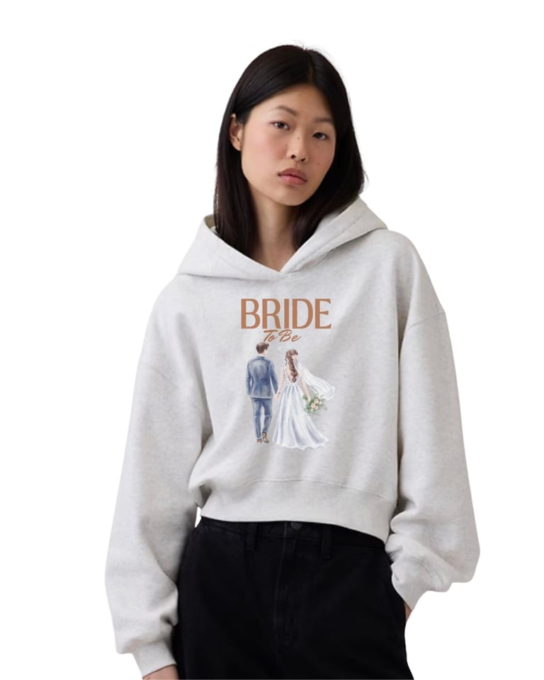 Woman wearing a light gray hoodie with BRIDE to Be text