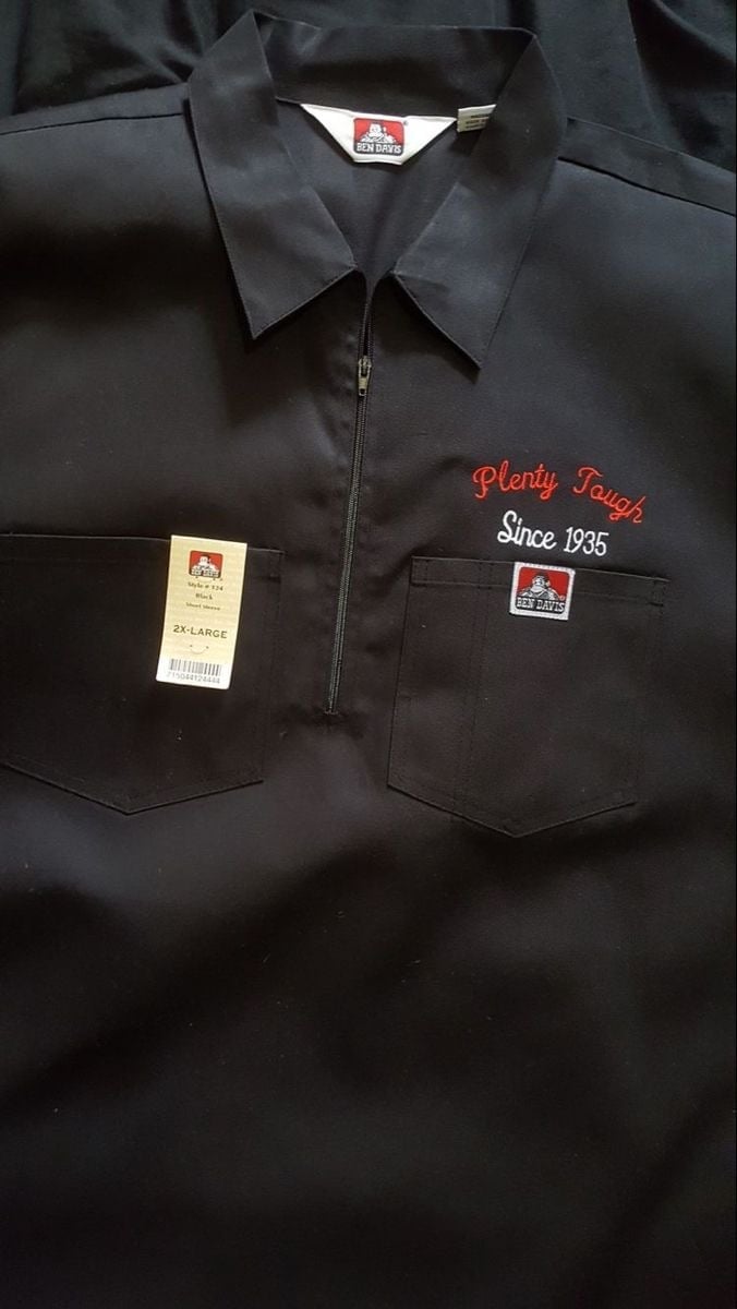 Black work shirt with Plenty Tough logo and Since 1935 text, featuring front pockets and half-zip closure with retail tags