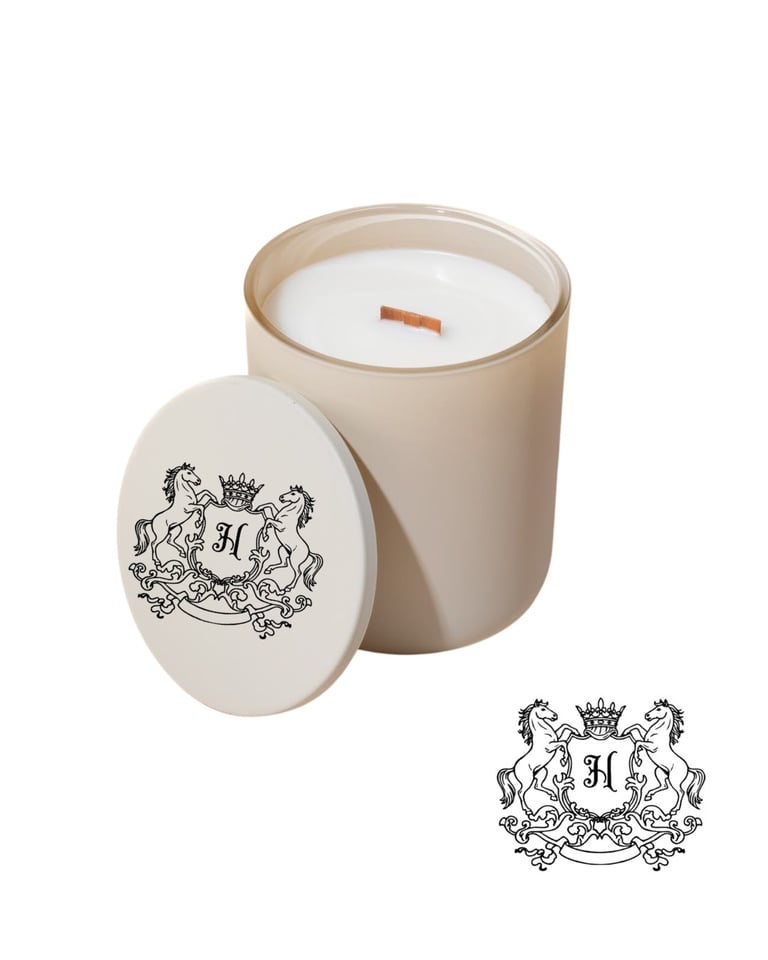 Cream-colored luxury scented candle in glass jar with heraldic crest lid and wooden wick